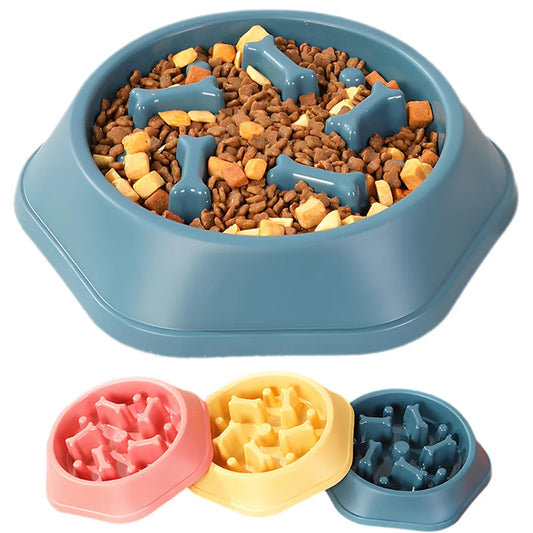 Close-up of blue slow feeder dog bowl with bone-shaped maze ridges holding kibble, with pink and yellow bowls