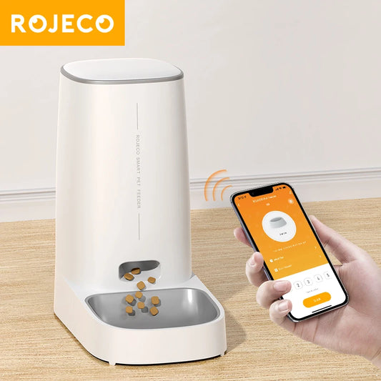 White ROJECO 4L automatic cat feeder dispensing dry kibble while a hand controls it from the app on a smartphone