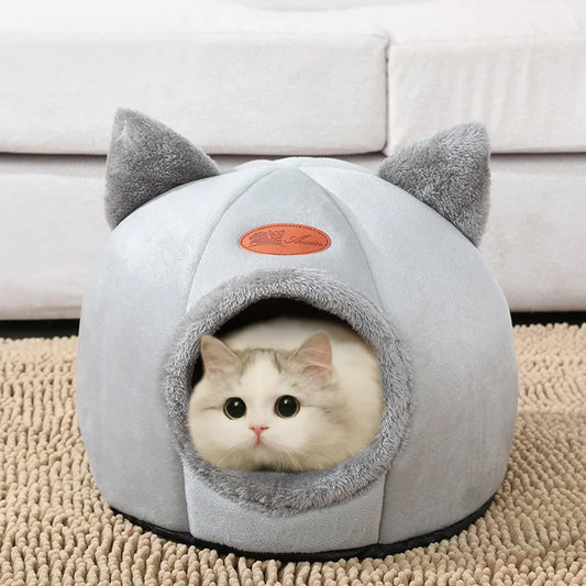 Cat resting inside a light grey enclosed cat cave bed on a beige carpet