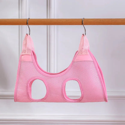 Pink mesh cat grooming hammock hanging from a wooden rail on two S-hooks