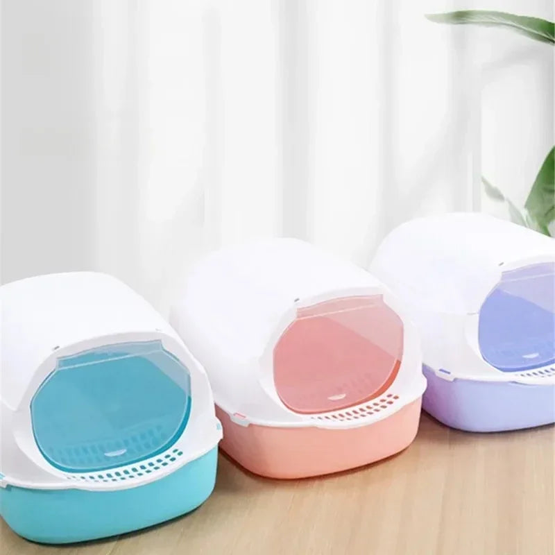 Three covered cat litter boxes in blue, pink and purple with hoods and swing door flaps