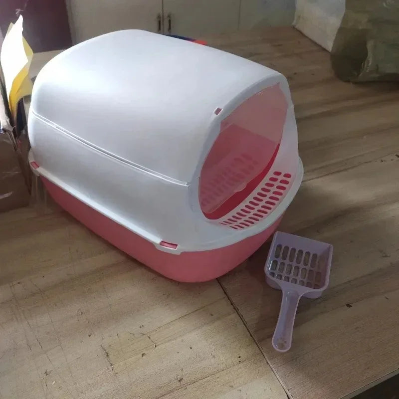 Pink hooded cat litter box with a litter scoop set up on a home floor